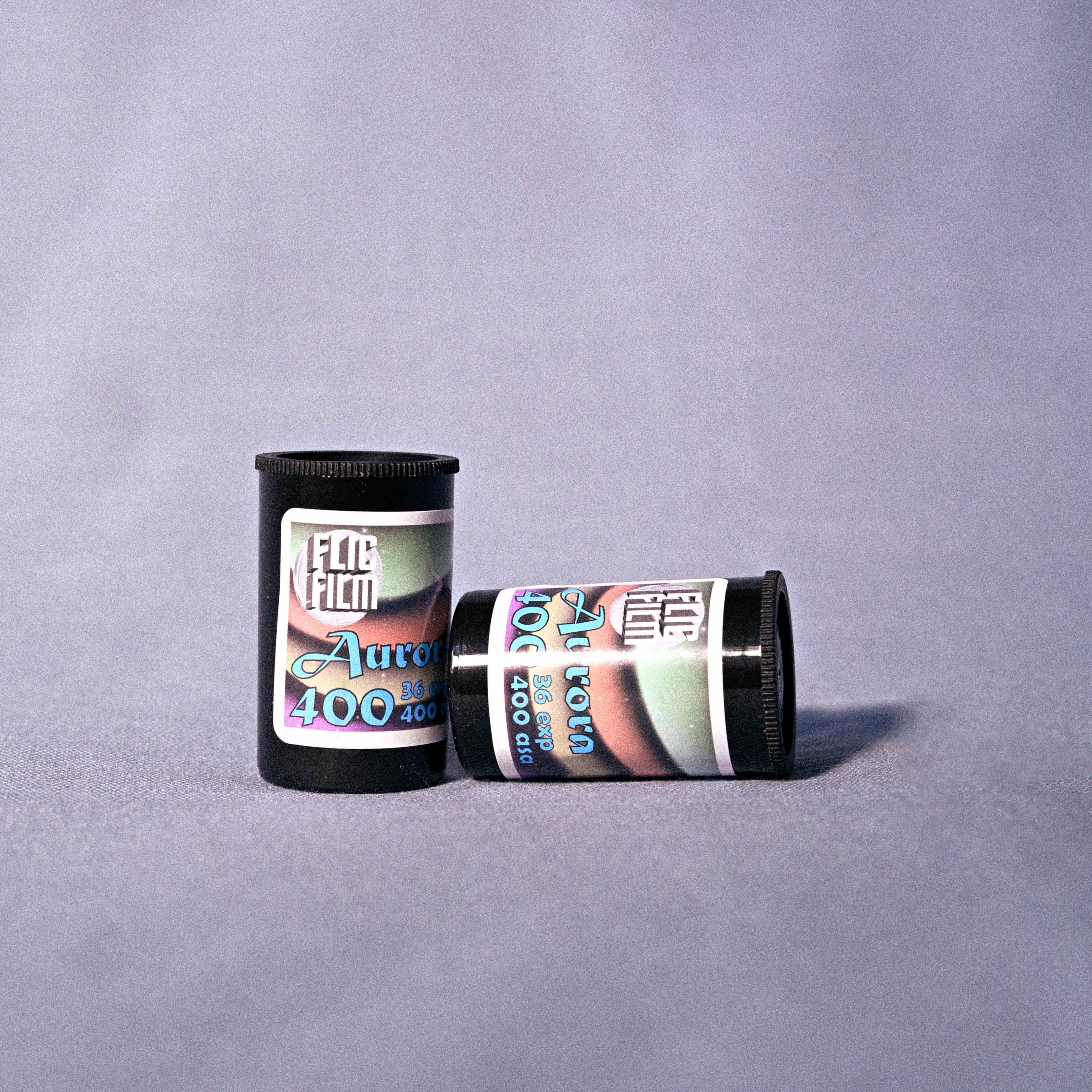 Two cannisters of Flic Film Aurora 400o 35mm film on  a gray background