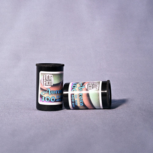 Two cannisters of Flic Film Aurora 400o 35mm film on  a gray background