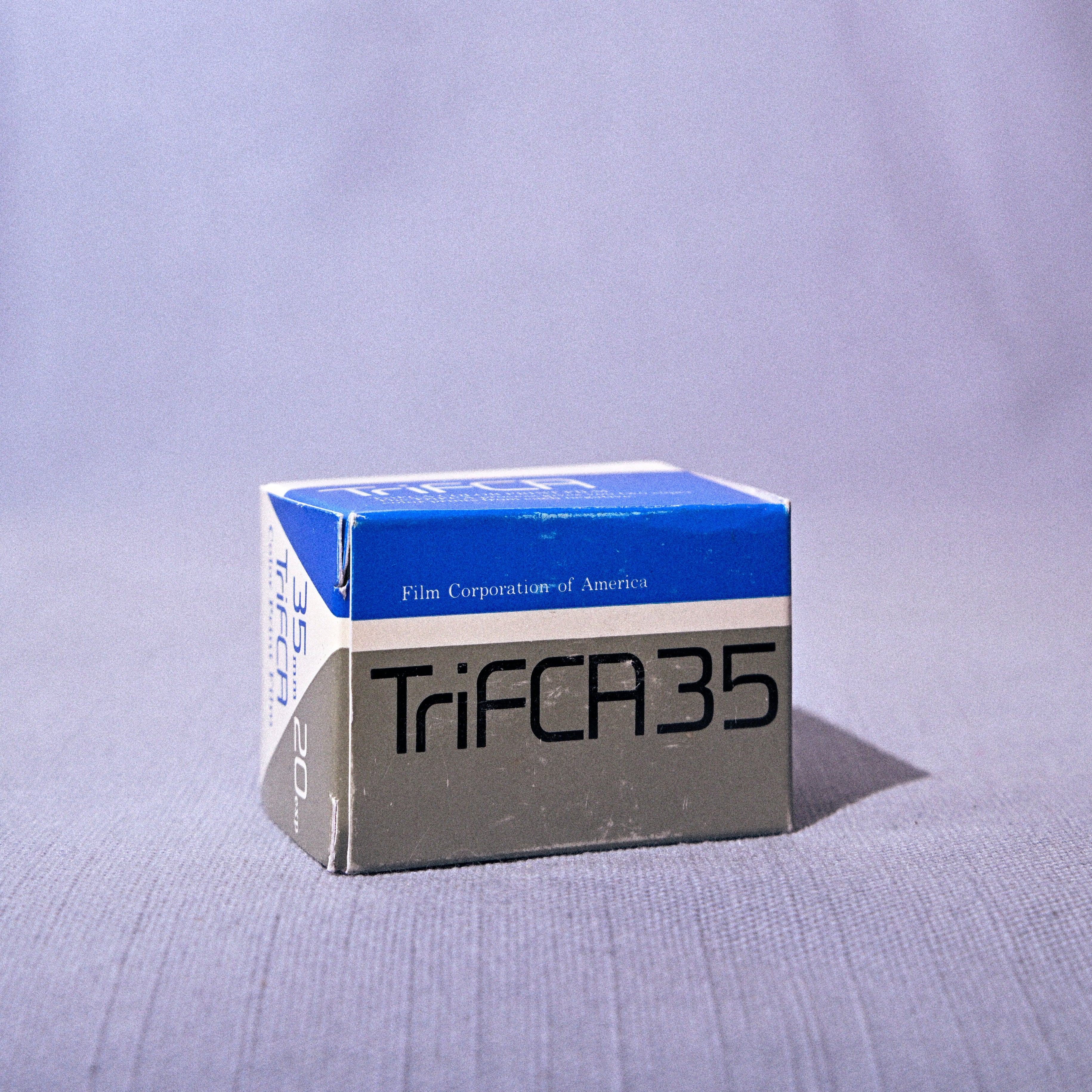 A vintage box of Tri-Fast 35 film, manufactured by Film Corporation of America, shown on a light gray fabric background.