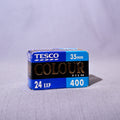A box of Tesco Colour Film 24 Exp 400, 35mm, standing on a light gray fabric surface against a matching gray fabric backdrop.