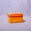 A vintage box of Kodak Panatomic-X film, showing its orange and yellow packaging, set against a plain light gray fabric backdrop.