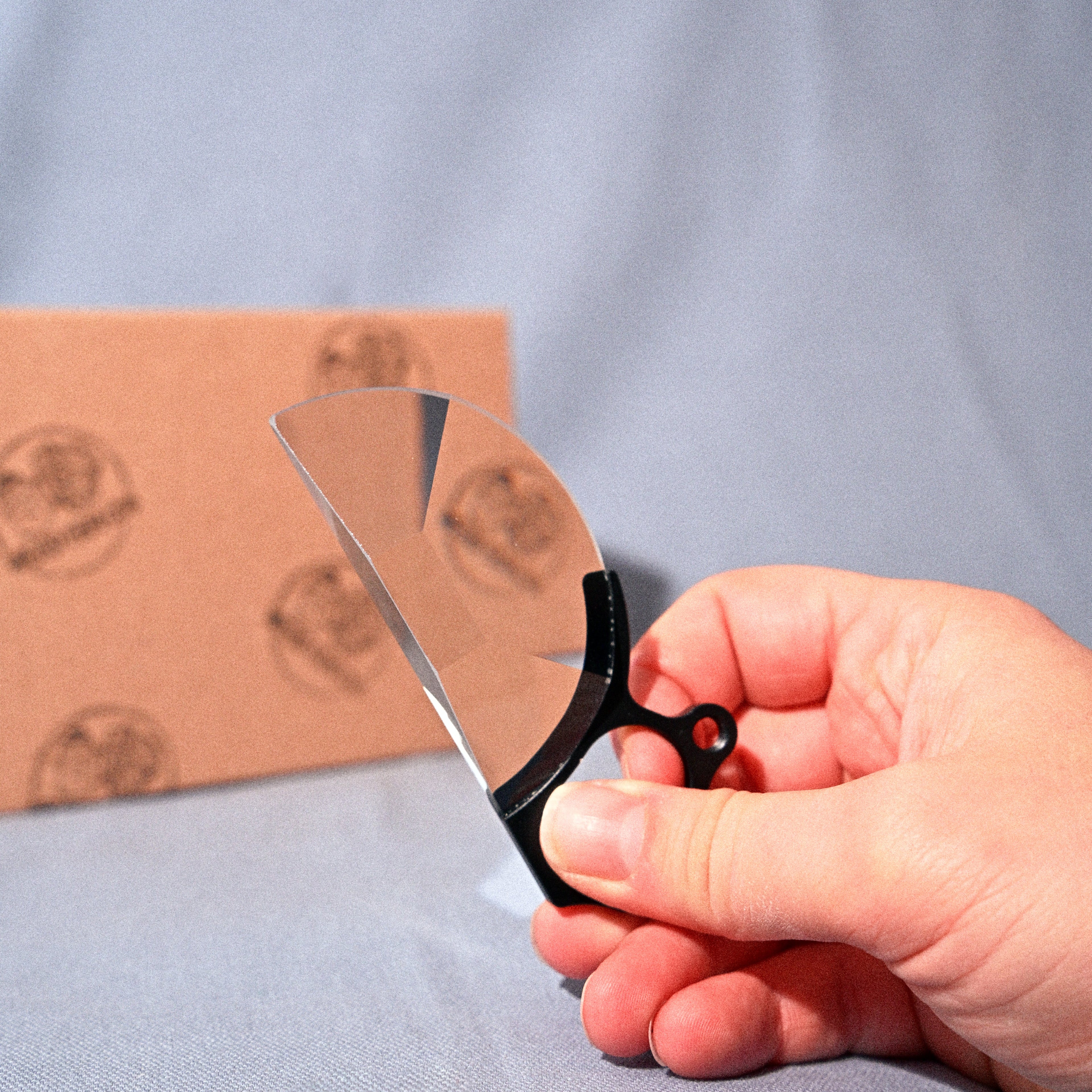 Hand holding a pair of scissors with a cardboard box in the background