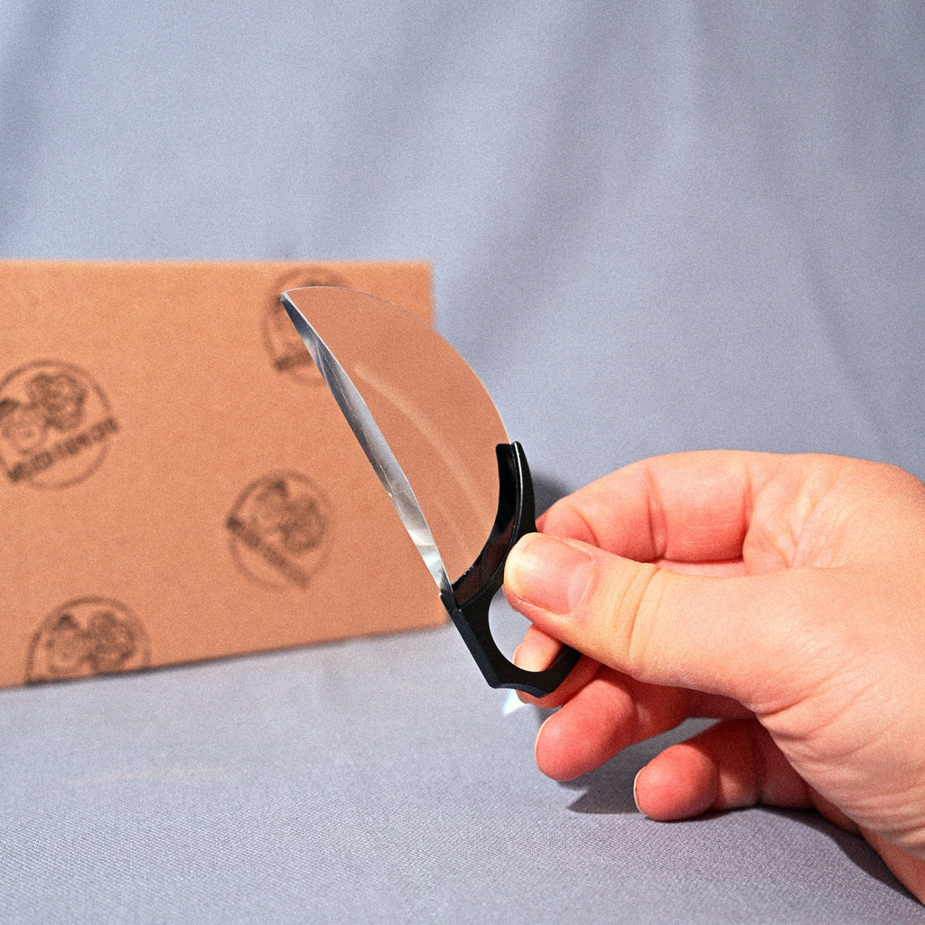 Hand holding a pair of scissors over a cardboard box on a blue background